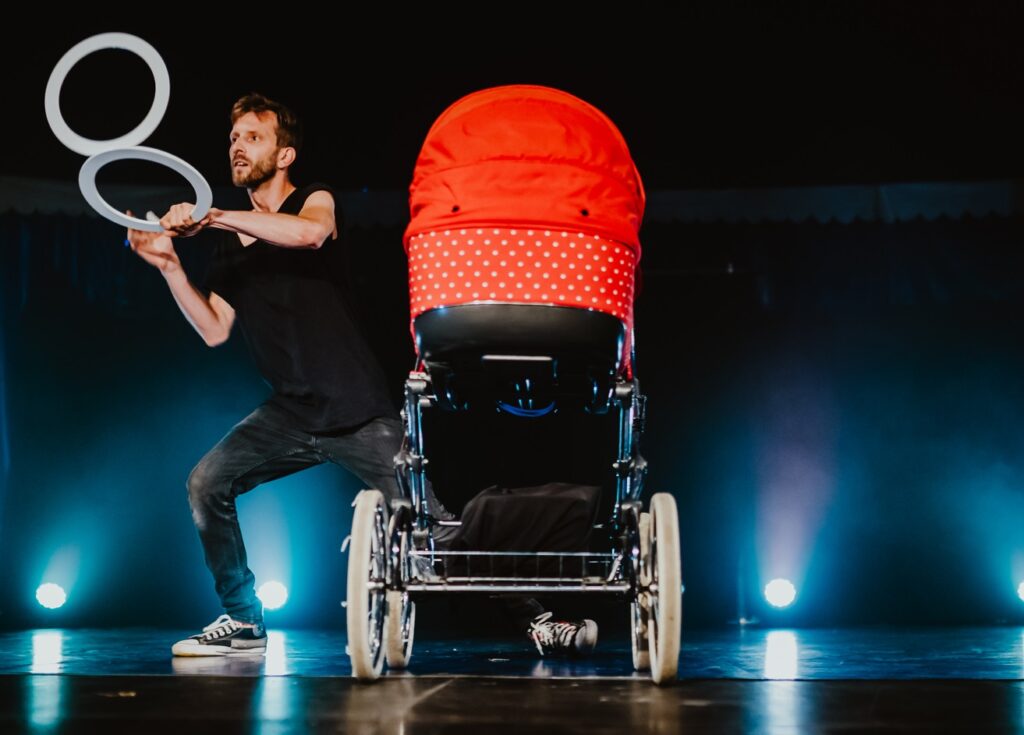 Artysta nowocyrkowy na scenie z wózkiem dziecięcym